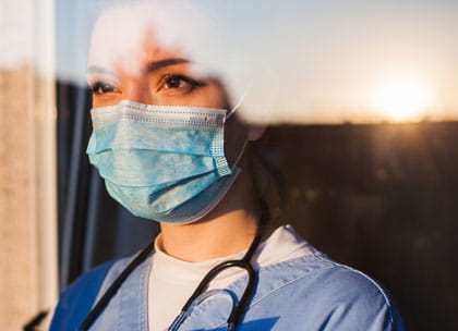 Young doctor looking out of window at sunrise